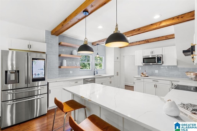 kitchen featuring appliances with stainless steel finishes, a peninsula, a sink, backsplash, and light stone countertops