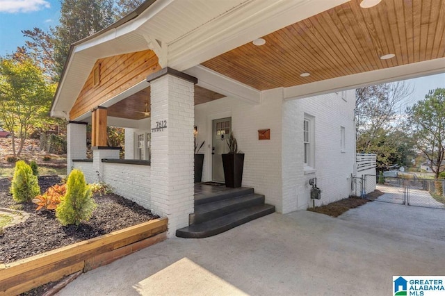 doorway to property featuring brick siding and a gate