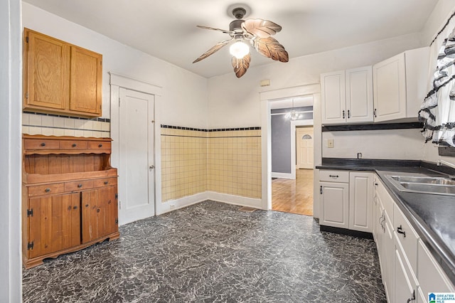 728 41st St, Fairfield, AL 35064 - kitchen with a ceiling fan, dark countertops, a sink, white cabinets, and tile walls