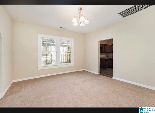 unfurnished room featuring carpet floors, a chandelier, and baseboards