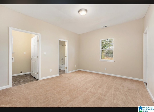 unfurnished bedroom with carpet flooring, ensuite bathroom, and baseboards