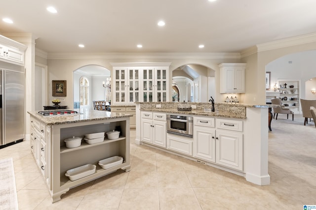 4035 Saint Charles Dr, Hoover, AL 35242 - kitchen featuring an island with sink, appliances with stainless steel finishes, open shelves, arched walkways, and white cabinetry