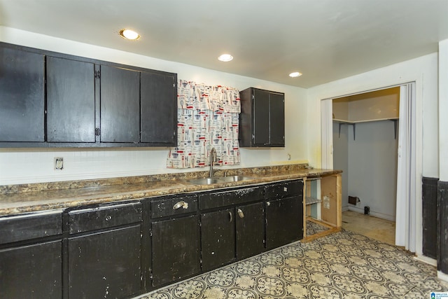 kitchen with a sink, dark cabinetry, dark countertops, recessed lighting, and decorative backsplash