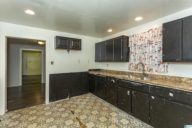 kitchen with a sink, recessed lighting, dark cabinetry, and dark countertops
