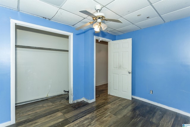 unfurnished bedroom with a drop ceiling, baseboards, wood finished floors, a closet, and ceiling fan
