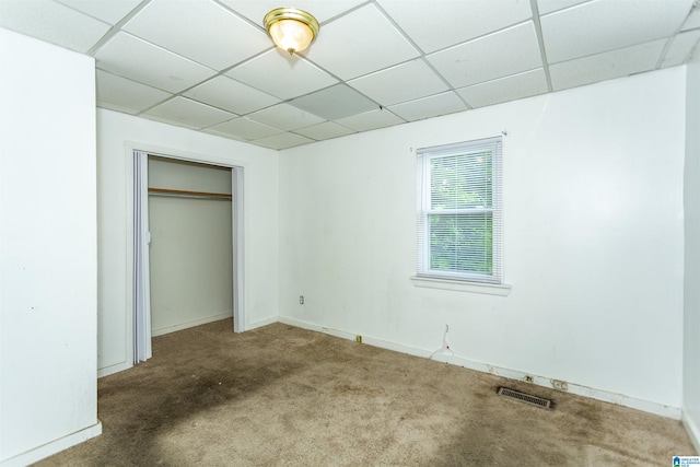 unfurnished bedroom featuring a paneled ceiling, carpet, a closet, and baseboards