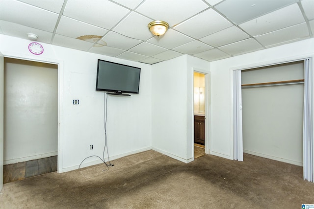 unfurnished bedroom with a drop ceiling, carpet flooring, baseboards, and a closet