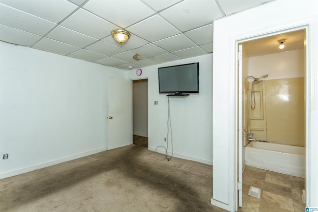 unfurnished bedroom featuring a drop ceiling, ensuite bath, and baseboards