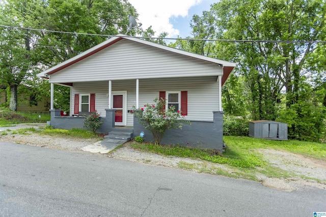bungalow-style home with a porch, a shed, and an outbuilding