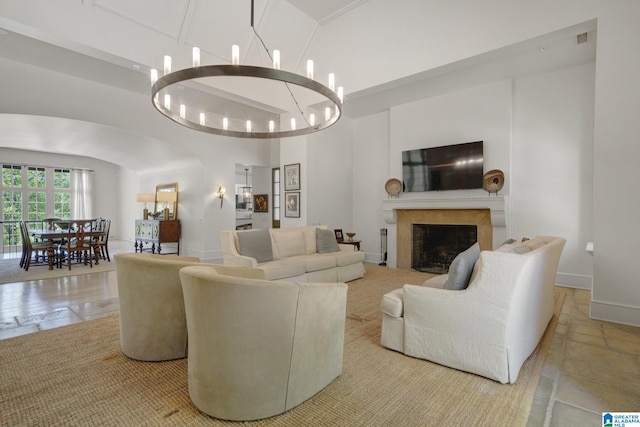 living room featuring a high ceiling, a chandelier, a fireplace, and baseboards