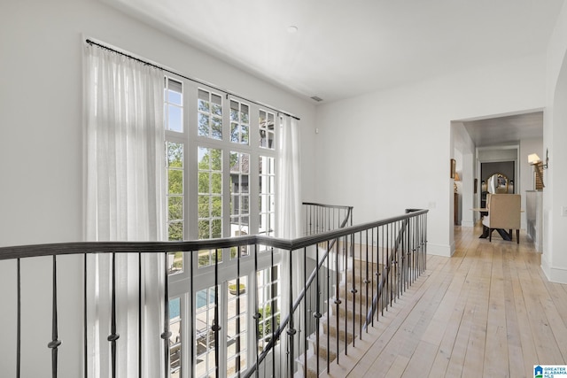 hallway with an upstairs landing, light wood-type flooring, and baseboards