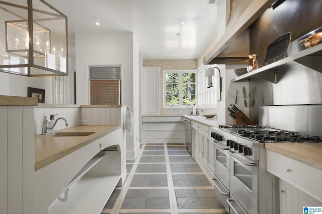 kitchen featuring stainless steel appliances, a sink, light countertops, white cabinetry, and inlaid floor details