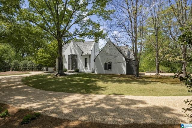 view of side of property featuring a yard, stucco siding, and a shingled roof