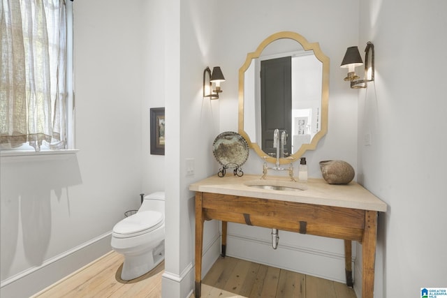 half bath featuring toilet, wood finished floors, and vanity