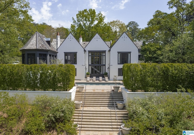 rear view of property featuring stucco siding, an outdoor pool, and a patio area