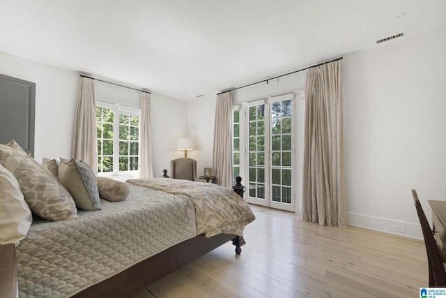 bedroom featuring multiple windows, access to outside, wood-type flooring, and baseboards