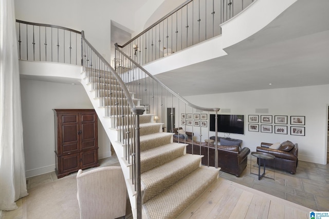 stairway featuring a towering ceiling and baseboards
