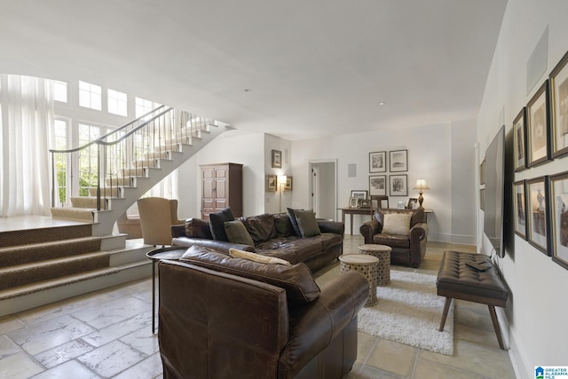 living room with stairway, baseboards, and stone tile floors