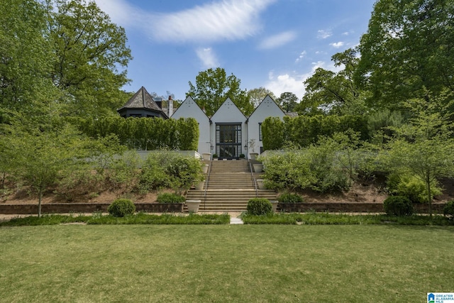 view of front facade with stucco siding, a front lawn, and stairs