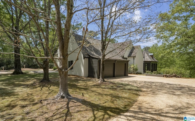 view of side of property with stucco siding, dirt driveway, and a garage