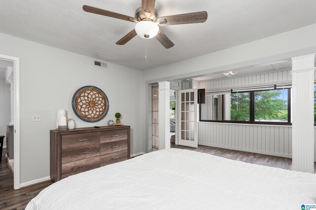 bedroom featuring ornate columns, wood finished floors, baseboards, and a ceiling fan