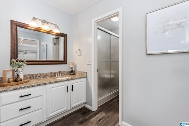 bathroom featuring wood finished floors, a stall shower, vanity, and baseboards