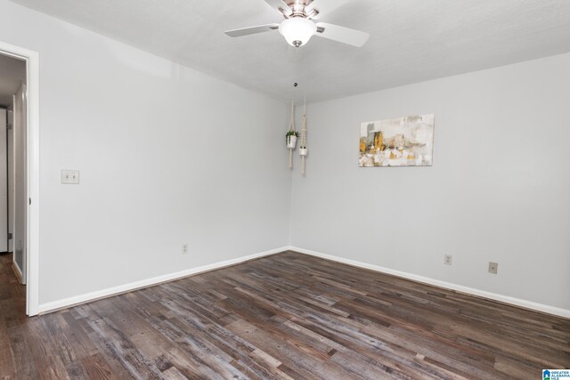 empty room featuring a ceiling fan, dark wood-type flooring, and baseboards