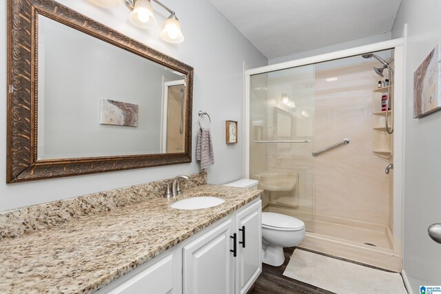 full bath featuring a stall shower, vanity, toilet, and wood finished floors