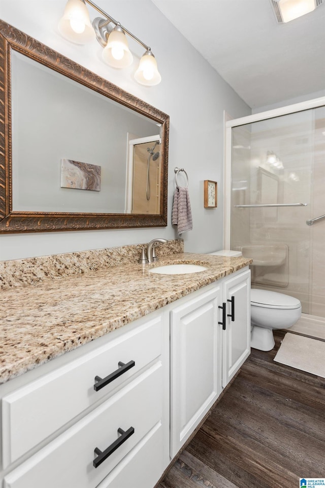 full bathroom featuring wood finished floors, a shower stall, toilet, and vanity