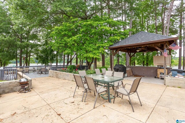 view of patio with outdoor dining space, a gazebo, fence, grilling area, and a jacuzzi