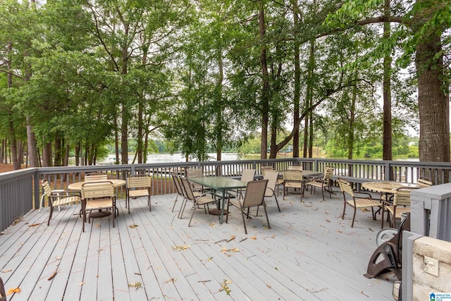 wooden terrace featuring outdoor dining space and view of wooded area