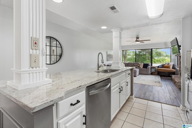 kitchen with a sink, stainless steel dishwasher, ornate columns, ceiling fan, and light tile patterned floors