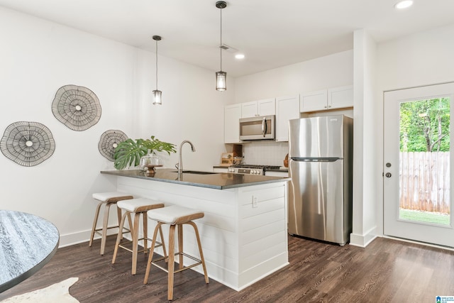 2213 3rd Ave S, Irondale, AL 35210 - kitchen featuring stainless steel appliances, dark countertops, dark wood-style flooring, backsplash, and a peninsula