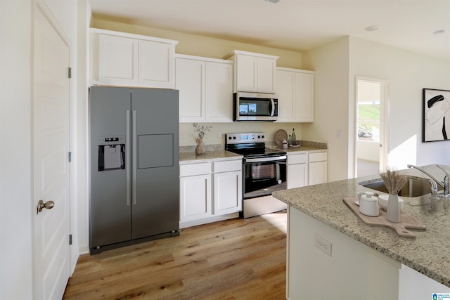 561 Boxwood Bnd, Calera, AL 35040 - kitchen featuring appliances with stainless steel finishes, a sink, white cabinets, light wood finished floors, and light stone countertops