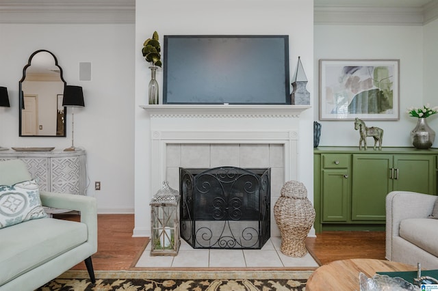 living room featuring wood finished floors, crown molding, a tile fireplace, and baseboards