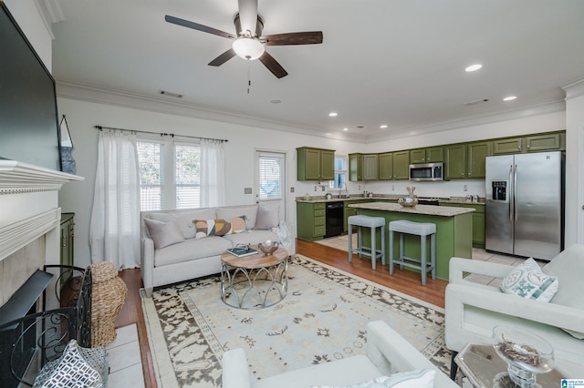 living area with ornamental molding, ceiling fan, a fireplace, light wood-style flooring, and recessed lighting
