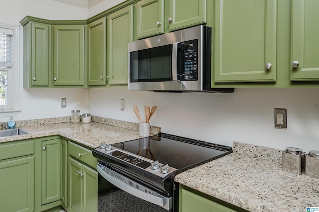 kitchen with appliances with stainless steel finishes, green cabinetry, and light stone countertops