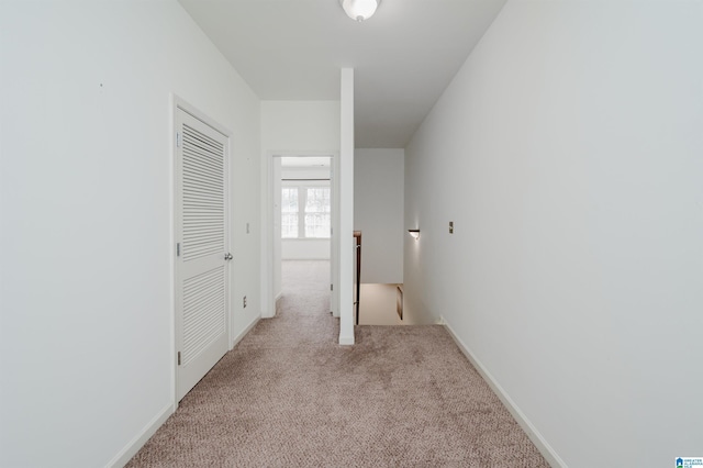 hall featuring an upstairs landing, carpet floors, and baseboards