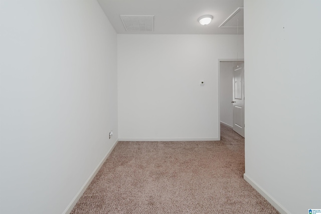 unfurnished room with attic access, carpet, and baseboards