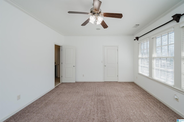 unfurnished bedroom with crown molding, light colored carpet, baseboards, and a ceiling fan