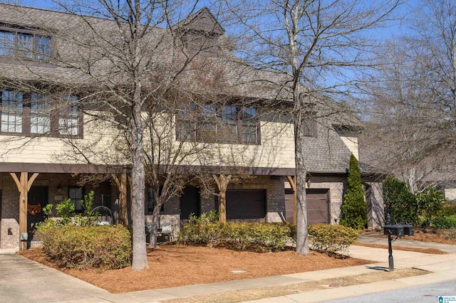 townhome / multi-family property with brick siding, a garage, and driveway