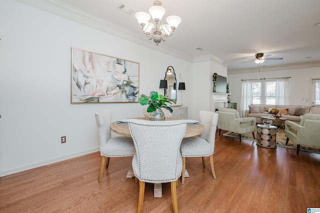 dining area featuring ornamental molding, a chandelier, wood finished floors, ceiling fan, and a fireplace