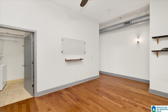 empty room featuring washer and clothes dryer, wood finished floors, baseboards, and a ceiling fan