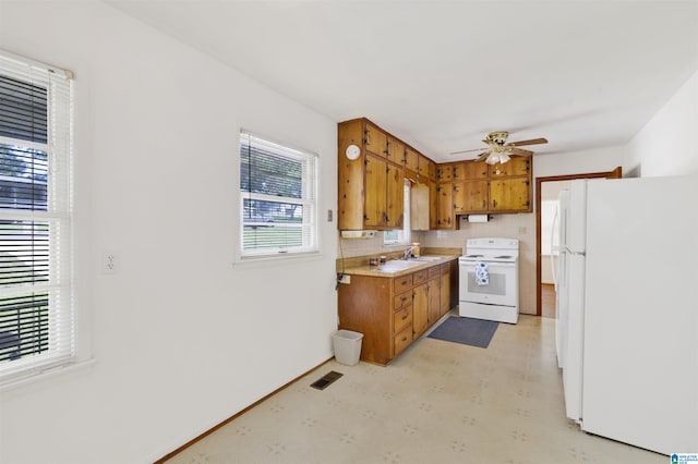 kitchen with white appliances, light flooring, a sink, brown cabinets, and light countertops