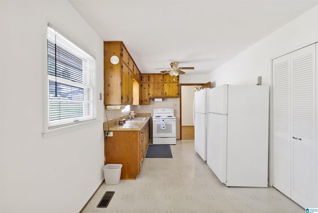 kitchen featuring white appliances, brown cabinets, ceiling fan, light flooring, and light countertops