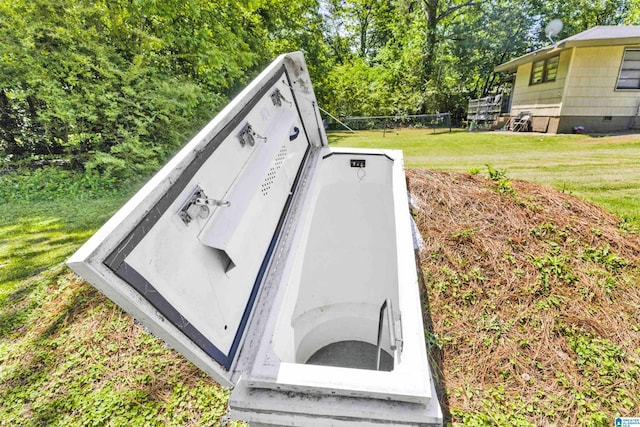 entry to storm shelter featuring a lawn and view of scattered trees