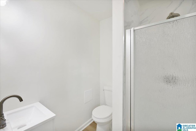 bathroom with a sink, a shower stall, and toilet