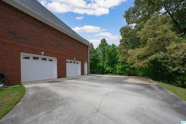 254 Macdonald Lake Rd, Springville, AL 35146 - view of side of home featuring concrete driveway, a garage, brick siding, and roof with shingles