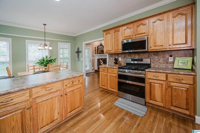 254 Macdonald Lake Rd, Springville, AL 35146 - kitchen with appliances with stainless steel finishes, light wood-style flooring, a chandelier, tasteful backsplash, and crown molding