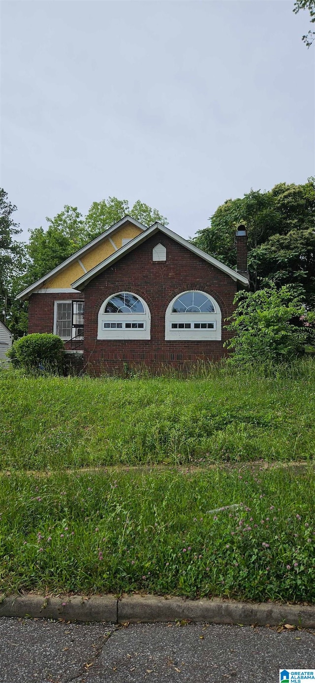 view of property exterior with a chimney and brick siding